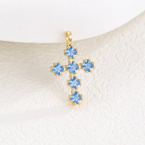 Gros plan du pendentif croix dorée serti de zircons bleus à coupe carrée