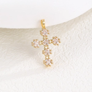 Vue macro d'un pendentif croix doré orné de six pierres de zircone cubiques carrées