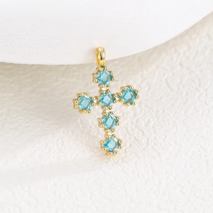 Macro de pendentif croix dorée avec six zircons bleus carrés et griffes de sertissage
