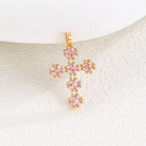 Gros plan d'un pendentif croix en or avec six zircons roses de coupe carrée pour femme