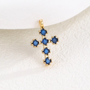 Vue macro du pendentif croix dorée avec six zircons bleus de taille carrée et griffes