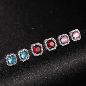 Macro detail van vierkante zirkoon oorknopjes in blauw, rood en roze met halo-stenen