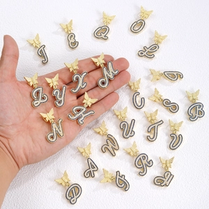 Macro detail of gold butterfly alphabet charms with inlaid blue cubic zirconia stones