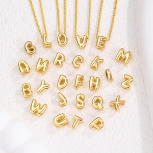 Detailansicht polierter goldener Blasen-Buchstabenanhänger an feinen Halsketten
