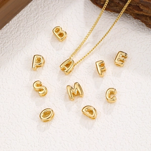 Polierte goldene 3D-Alphabet-Anhänger und Buchstabenkette auf natürlichem Hintergrund