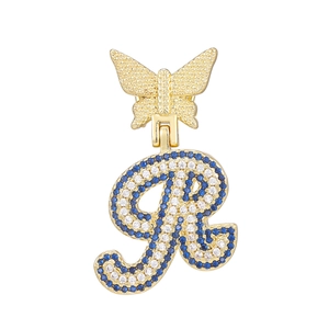 Detail of golden butterfly clasp and large letter R pendant with blue and clear crystals