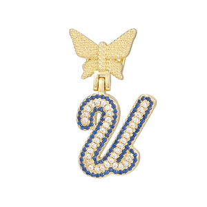 Macro view of gold butterfly pendant with sparkling blue and white letter U zircon