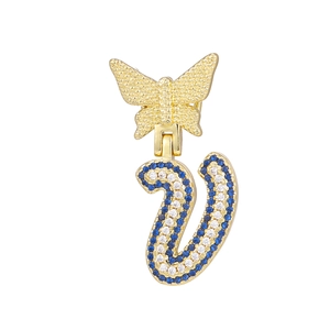 Detail of gold butterfly pendant with a sparkling blue and white crystal V letter charm