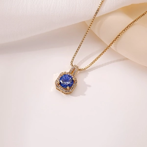 Detalle macro del colgante halo dorado con piedra azul profunda y pavé de circonitas