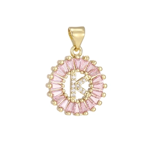 Macro view of gold-plated pendant with letter K, pink crystals and zircon stones
