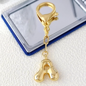 Portachiavi con lettera A bombata in oro 18K e chiusura a moschettone su sfondo specchio