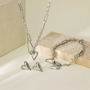 Nahaufnahme von silbernem Herzschmuck-Set mit polierten Kettengliedern auf Stein