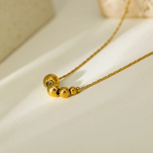 Macro shot of five gradient gold beads on a delicate titanium steel necklace