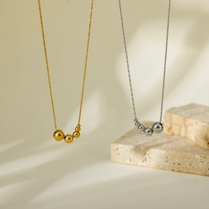 Detailed view of gold and silver minimalist bead pendants on fine stainless steel O-chains