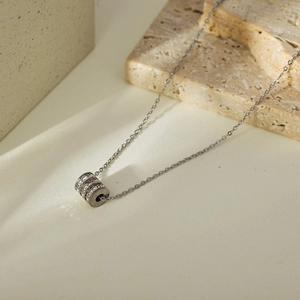 Macro view of triple cylinder pendant with embedded crystals on a textured stone base