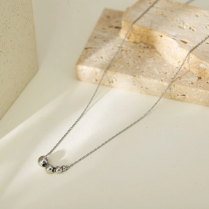 Minimalist silver titanium steel necklace with five graduated metal beads on fine chain