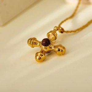 Macro detail of vintage gold cross necklace with tiger eye stone and polished finish