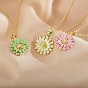 Detailed view of three enamel sunflower pendants in mint, white, and pink on gold chains