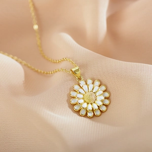 Macro view of white enamel sunflower pendant with gold petals on soft fabric