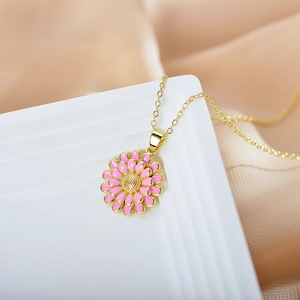 Detail of pink enamel sunflower pendant on a gold chain over champagne satin fabric