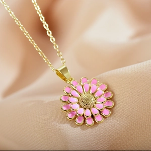 Macro view of pink enamel daisy pendant with golden layered petals on satin fabric