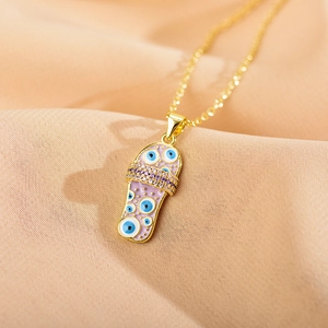 Macro shot of gold necklace with evil eye flip-flop pendant on silk fabric