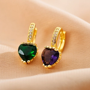 Détail de boucles d'oreilles cœur en zircone dorée avec des pierres vertes et violettes