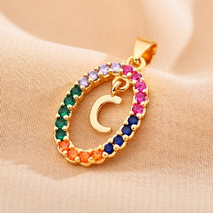 Macro detail of a gold oval pendant with multi-color crystals and letter C