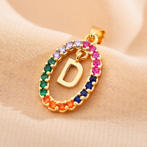 Detail of gold letter D pendant with multi-color zircons on textured fabric