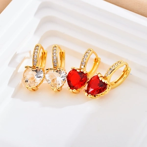 Détail de boucles d'oreilles cœur en cuivre avec zircon rouge et pierres claires