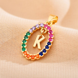 Macro detail of gold letter K pendant with colorful zircon stones on a chain