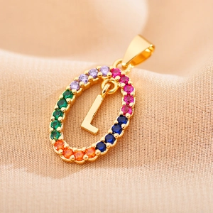 Macro shot of gold oval pendant with colorful zircons and capital letter L detail