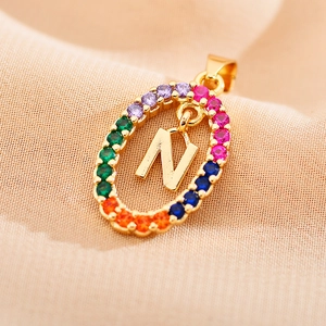 Macro shot of gold oval pendant featuring letter N and multi-color zircon stones
