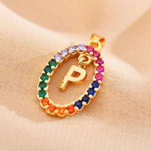 Macro shot of oval gold necklace pendant with rainbow zircon stones and letter P detail