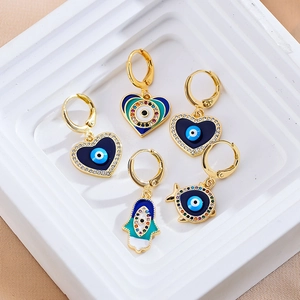 Macro-detail van boze oog oorbellen set met hamsa en hart bedeltjes en zirkonia inlay