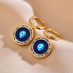 Detail van gouden Evil Eye oorbellen met blauw email en kleurrijke strass-steentjes