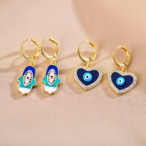 Detailopname van Hamsa-hand en hartvormige boze oog oorbellen met zirkonia accenten