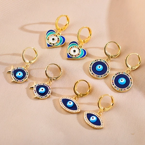 Detail van vier paar gouden evil eye oorbellen met blauw emaille en fonkelende steentjes