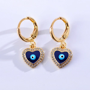 Gouden hartvormige oorbellen met blauw oog hanger en kristallen op witte achtergrond