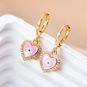 Macro detail van roze hartvormige oorbellen met evil eye en ingezette zirkonia steentjes