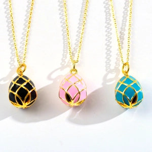 Three elegant egg-shaped planet pendants in black, pink, and blue with gold mesh chains