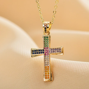 Detail of cross pendant with colorful zircon stones and golden chain on silk fabric