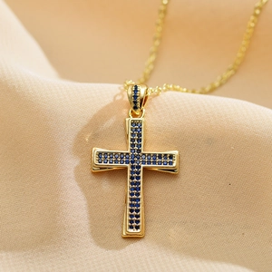 Macro shot of gold cross pendant with micro-pave blue cubic zirconia on silk fabric