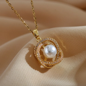 Macro shot of a white pearl pendant necklace with zircon bird nest design in gold finish