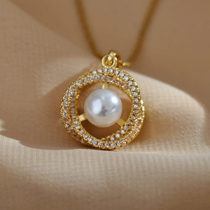 Macro detail of white freshwater pearl necklace with gold nest pendant and zircons