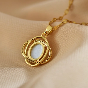 Nahaufnahme der goldenen Kette mit hellblauem ovalen Stein und diamantbesetzten Ringen