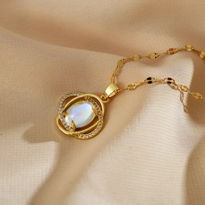 Makroaufnahme der Goldhalskette mit verschlungenen Ringen und Mondstein-Anhänger
