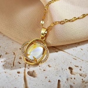 Detailansicht eines goldenen Kleeblatt-Anhängers mit Opal und funkelnden Kristallen