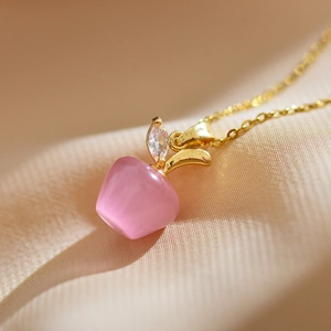 Macro d'un pendentif pomme en œil de chat rose avec feuille dorée et zircon