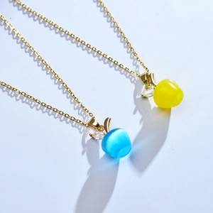 Détail macro de pendentifs pomme œil-de-chat bleus et jaunes avec feuille d'or et zircon